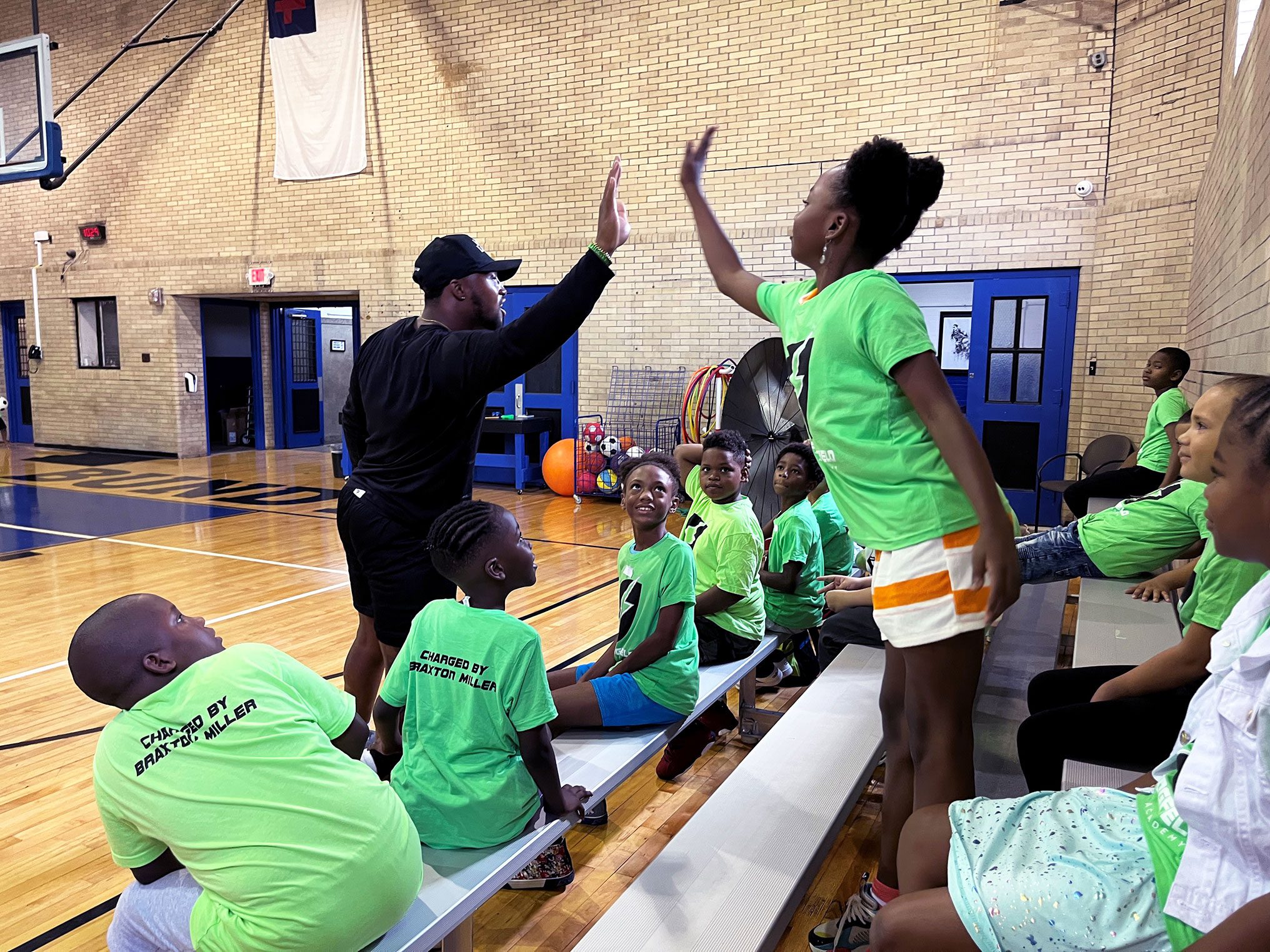 Students in the gymnasium with the teacher high-fiving one another